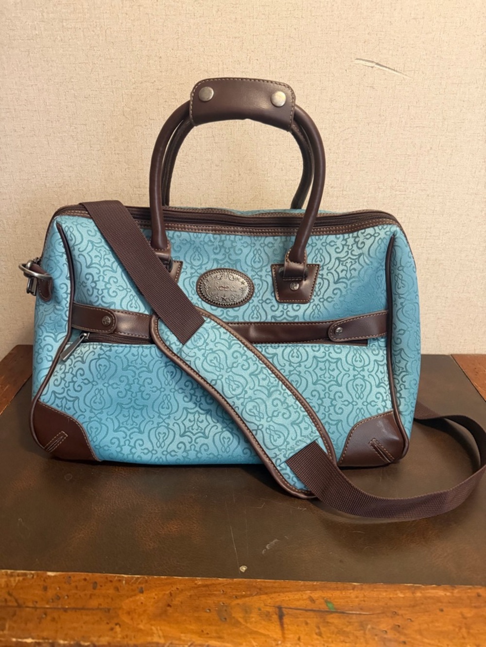 Blue Patterned Travel Bag with Brown Trim and Shoulder Strap